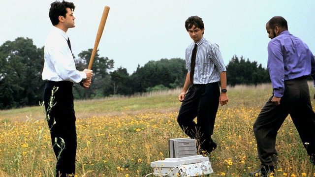 Scene from the movie office space where recently laid off employees are smashing a printer